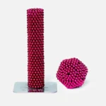 Bunte magnetische Kugeln in Pink, geformt zu einer Turm- und einer Ballskulptur, die auf einer weißen Oberfläche stehen.