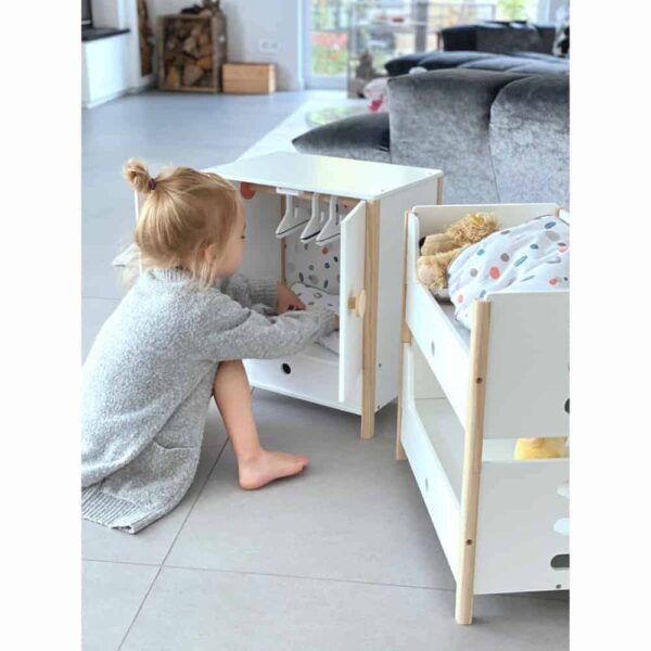 Der Small Foot Puppenschrank aus der Reihe „Little Button“ bietet mit einer Höhe von 48 cm viel Platz für Puppenkleider aller Art. Mit den leicht gängigen Flügeltüren kannst du den Puppenschrank bequem öffnen. Im Inneren findest du deine Kleiderstange und ein Fach, um Sachen zu verstauen. Ebenfalls enthalten sind spezielle Kleiderbügel, die über ein Gummiband verfügen. Damit eignen sie sich auch gut, um kleine Teile wie Schuhe oder Tücher zu verstauen. Um sicheres Spielen zu gewährleisten, sind alle Kanten abgerundet. Die weiße Farbgebung des Puppenschranks weiß sowohl Mädchen als auch Jungen zu gefallen. Der Schrank ist für Kinder ab 3 Jahren geeignet und passt perfekt zu allen anderen Produkten der „Little Button“-Reihe.