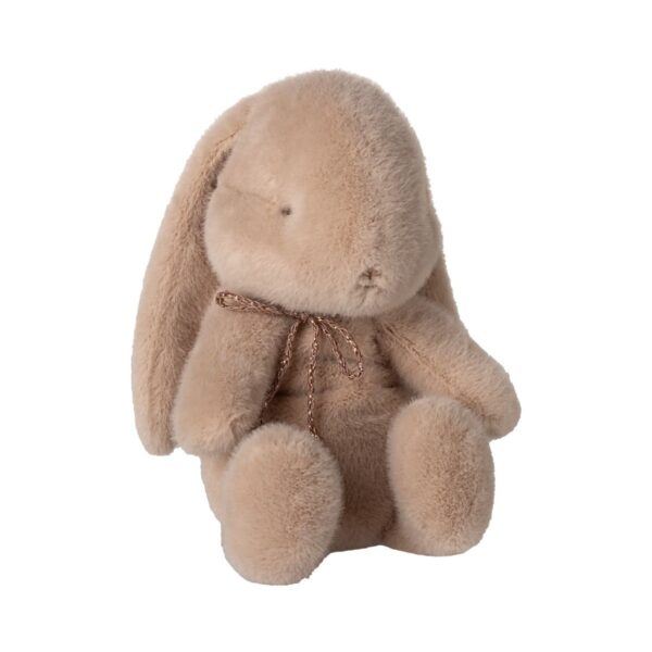 Weicher, beiger Plüsch-Hase mit langen Ohren und braunem Schnurband um den Hals, sitzt auf weißem Hintergrund.